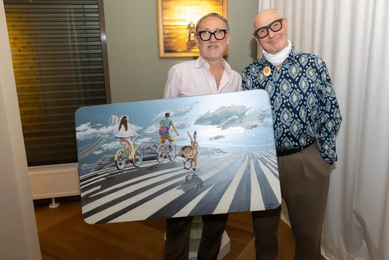 Zwei Männer präsentieren das Bild „Unbekannte Reise“ von Beni Altmüller bei Kunst & Kulinarik 2026