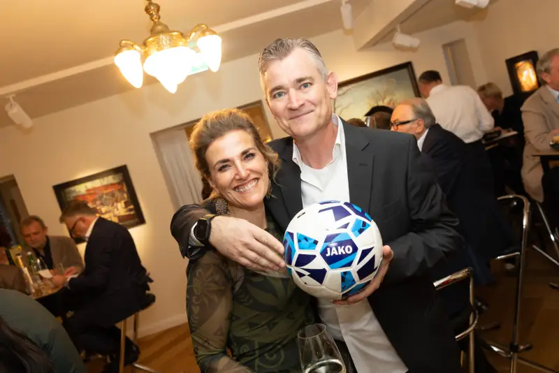 Zwei Gäste mit dem versteigerten Fußball bei Kunst & Kulinarik 2026
