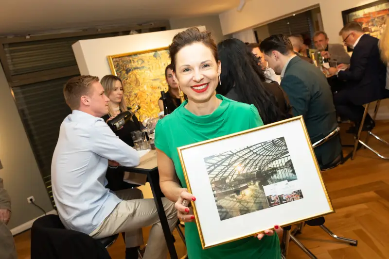 Gästin mit einem ersteigerten gerahmten Bild bei Kunst & Kulinarik 2026